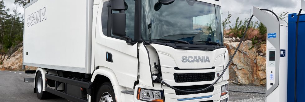 Weißer Scania-Lkw tankt an einer Stromladesäule