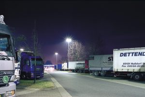 Viele Lkw stehen auf einem Lkw-Parkplatz auf einem Rasthof bei Nacht