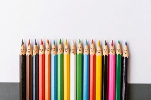Buntstifte mit Gesicht neben einander aufgereiht symbolisieren Vielfalt